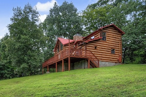A log cabin with a wooden deck and a red roof, surrounded by lush greenery. - Welcome to Biltmore Escape, your perfect Sevierville retreat nestled in the hear (Sevierville)