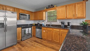 A kitchen with wooden cabinets, stainless steel appliances, and a granite countertop. - Welcome to Biltmore Escape, your perfect Sevierville retreat nestled in the hear (Sevierville)