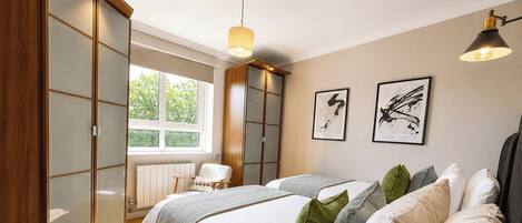 Un dormitorio con una cama grande, una silla, un ventanal y un armario.