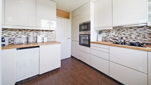 Eine moderne Küche mit weißen Schränken, einer gefliesten Spritzschutzwand und einer Holzarbeitsplatte.