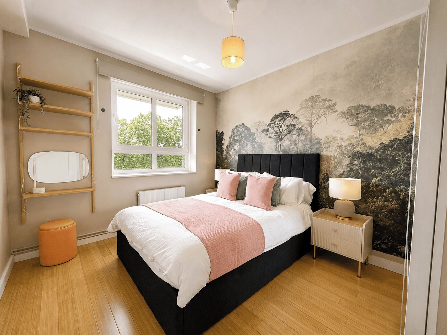 A bedroom with a bed, bedside table, lamp, window, and wall art.