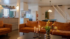 Un espacio de sala acogedor con un sofá, una mesita de centro con velas y un jarrón de flores.
