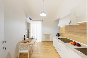 Eine kleine Küche mit weißen Schränken, einer Holz Arbeitsplatte und einer hängenden Pendelleuchte.