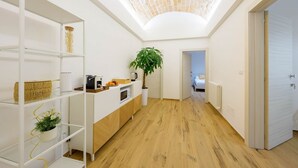 A modern kitchen with a skylight, wooden flooring, and a white interior.
