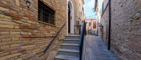 A narrow alleyway with stone walls, a set of stairs, and a small door at the top.