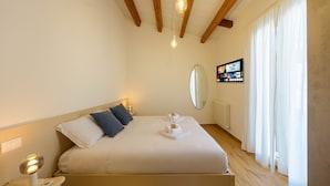 Une chambre à coucher avec un lit, une table de chevet, une lampe et un grand miroir au mur.
