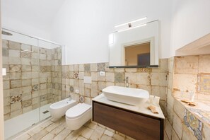 Ein Badezimmer mit Duschkabine aus Glas, einem weißen Waschbecken und einem Spiegel darüber.