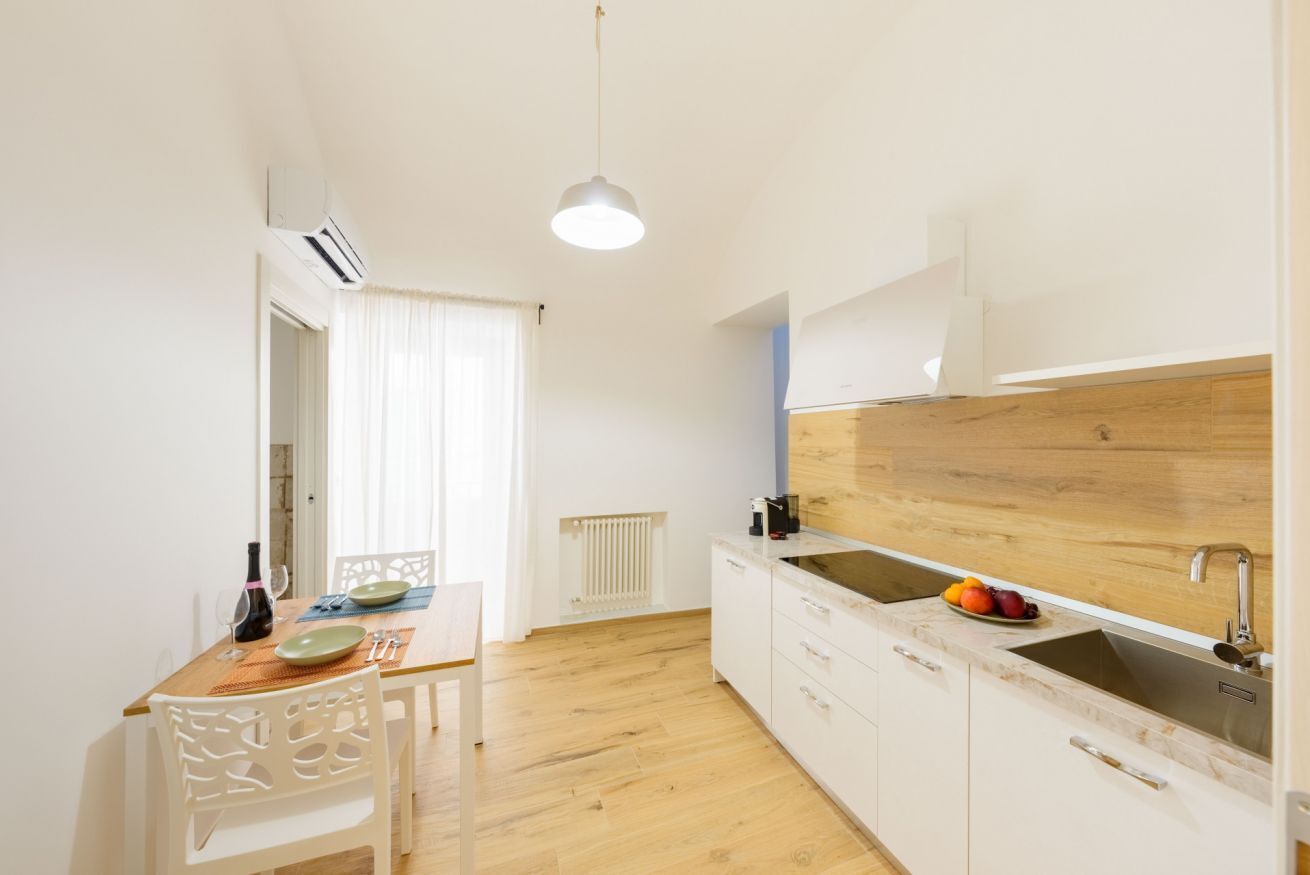 A modern kitchen with a wooden countertop, white cabinets, and a built-in sink.