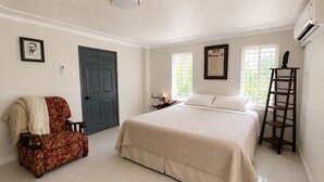 Ein Schlafzimmer mit einem Bett, einem Sessel, einer Tür, einem Fenster und einer Leiter.