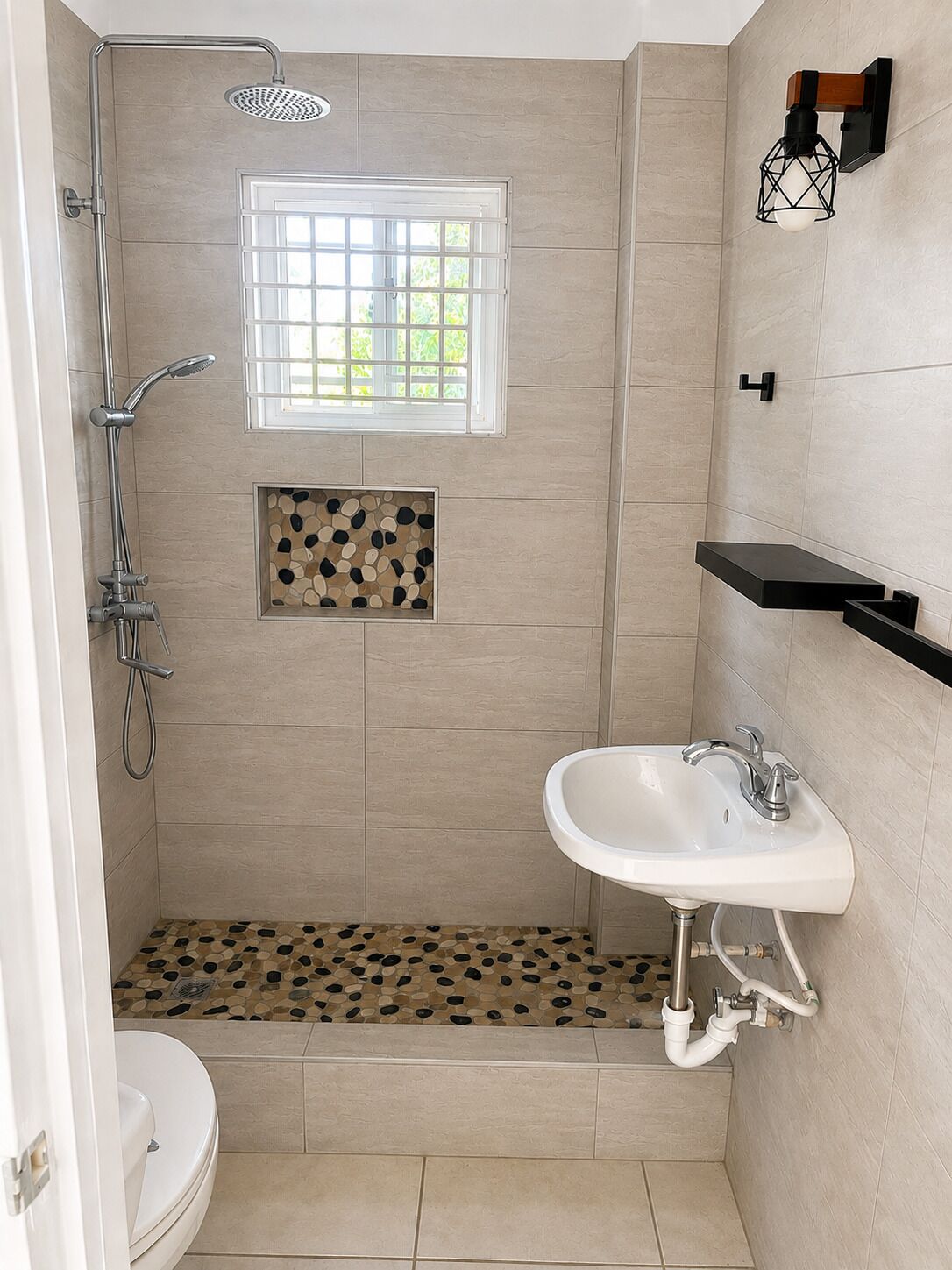 A bathroom with a shower, toilet, sink, and a window with a view.