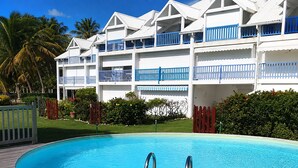 Um hotel com piscina, várias varandas e um jardim tropical.