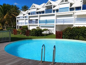 Ein Hotel mit Pool, mehreren Balkonen und einem tropischen Garten.