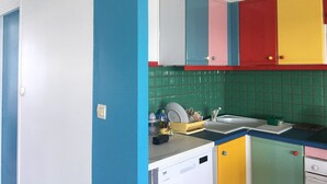 Uma cozinha com armários coloridos, uma pia e um escorredor de louça.