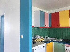 Eine Küche mit farbenfrohen Schränken, einem Spülbecken und einem Geschirrgestell.