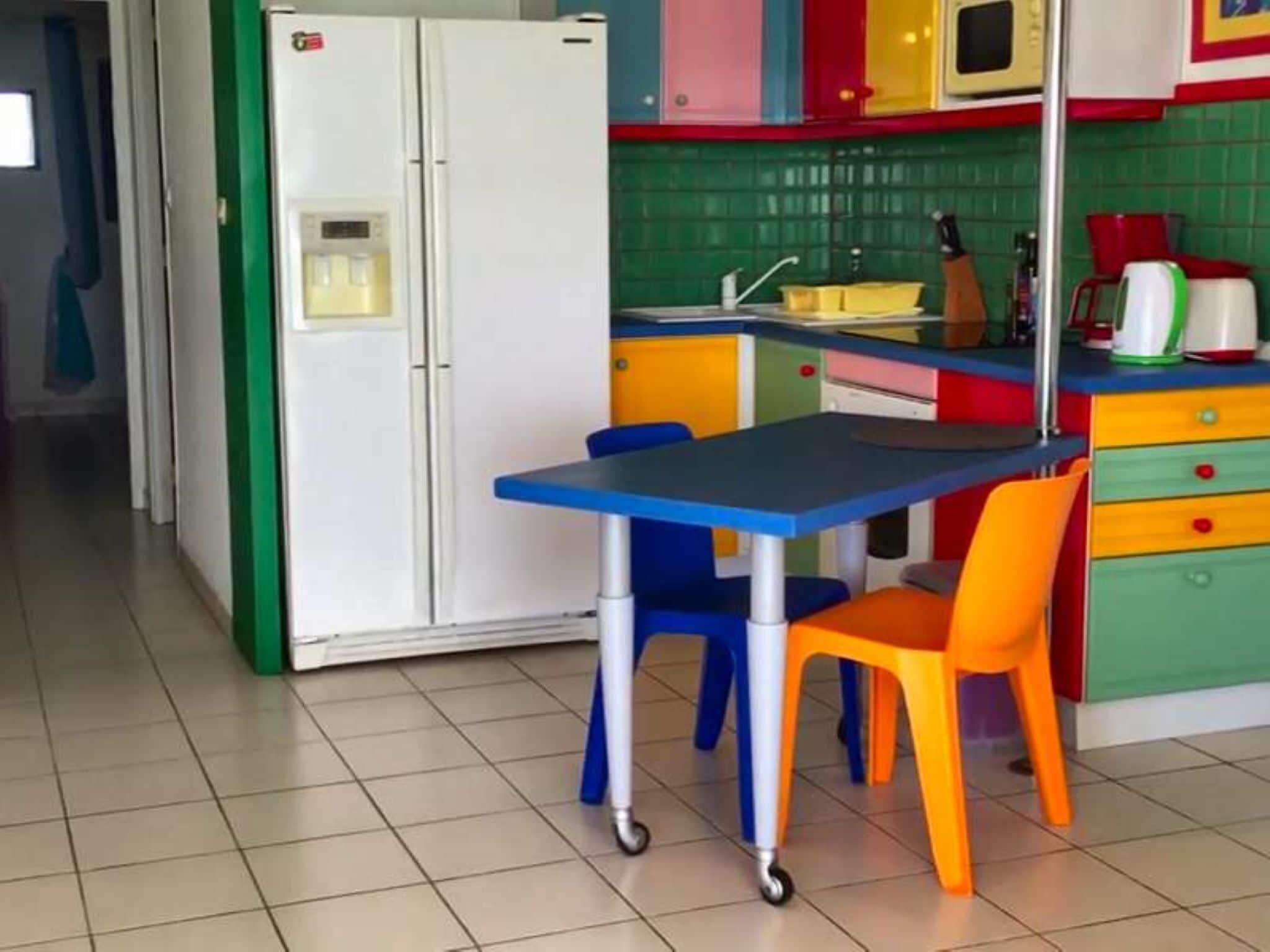 A kitchen with a refrigerator, sink, and colorful cabinets.