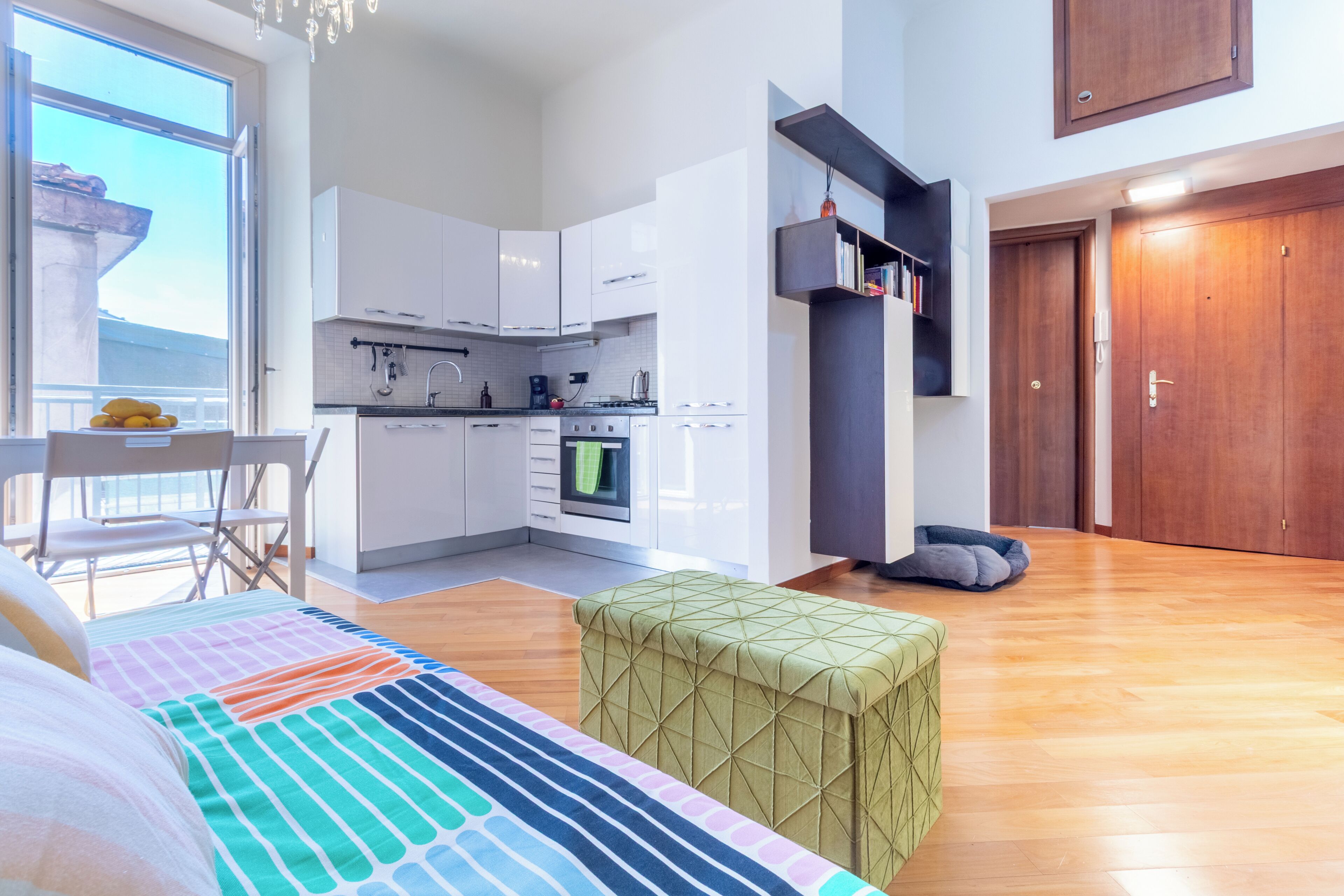 Un appartement moderne comprenant une cuisine, un coin repas, un lit et un balcon.