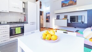 Een moderne keuken met witte kasten, een fornuis en een eethoek met een tafel en stoelen.