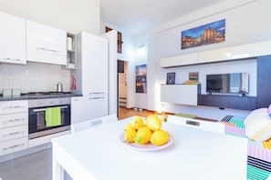 A modern kitchen with white cabinetry, a stove, and a dining area with a table and chairs. - 5 minutes from the M5 Metro station, Università Bicocca, with a private garage (Milano)