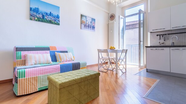 Een modern appartement met een bank, een eettafel en een kitchenette.