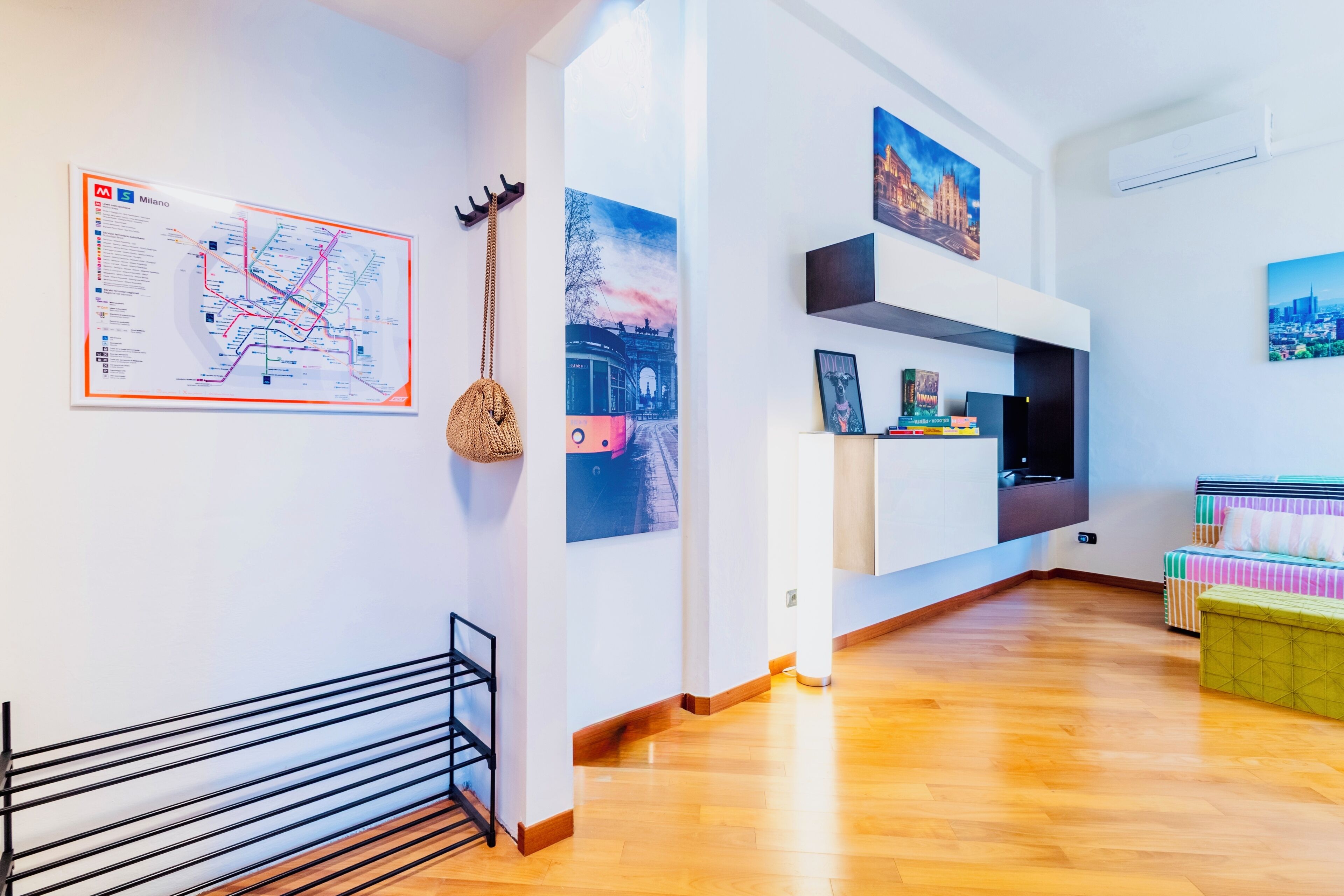 Un salon moderne avec un plancher en bois, une carte accrochée au mur, un panier suspendu et un canapé agrémenté de coussins à rayures.
