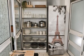 A kitchen with a wall-mounted shelf holding various kitchenware and a decorative item depicting the Eiffel Tower. - Studio for 2 people near the sea, Dziwnówek (Dziwnówek)