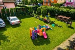 A residential area with a well-maintained lawn, a children's play structure, and parked cars.