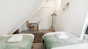 Une chambre avec deux lits, un bureau et une chaise.