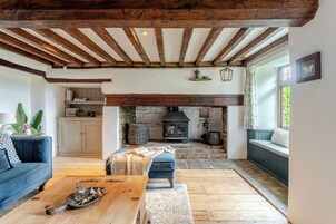 A cozy living room with a fireplace, wooden beams, a sofa, and a coffee table.