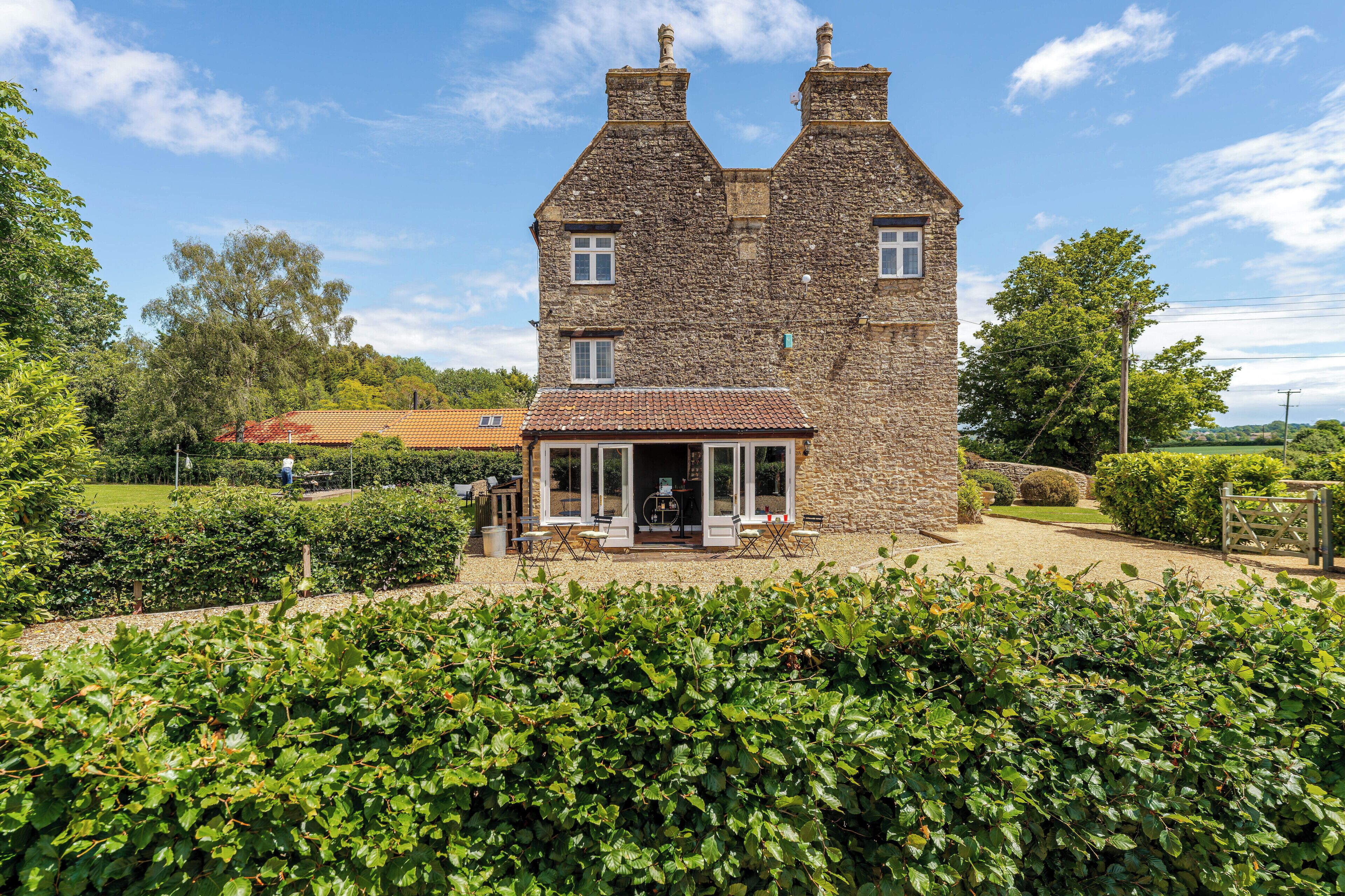 A stone building with a traditional design, featuring a front entrance with glass doors and a small patio area.