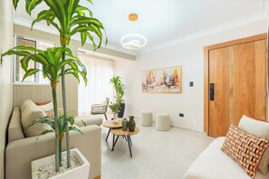 A living room with a sofa, a coffee table, a potted plant, a painting on the wall, and a wooden door. - View of Pontezuela (Santiago de los caballeros)