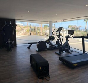 A gym with exercise equipment, a bench, and a treadmill. - Beachfront apartment with spectacular ocean views! Relax and unwind! (AN)