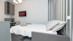 Ett modernt sovrum med en säng, ett sängbord och en väggmonterad TV som visar ”NETFLIX”.