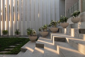 A modern building with vertical columns, outdoor steps, and potted plants. - Breeze 5-18 | Oceanfront Villa | Infinity Pool (Cruz de Huanacaxtle)