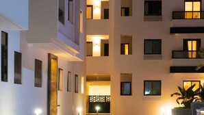 Un immeuble à plusieurs étages, doté de fenêtres illuminées et d’une entrée centrale.