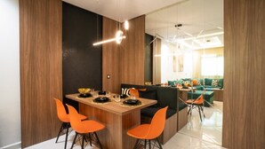Un espace repas moderne avec une table en bois, des chaises orange et un chemin de table noir et blanc à motifs.