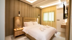 Une chambre d’hôtel moderne avec un grand lit, une table de chevet avec une lampe, un téléviseur fixé au mur et une fenêtre avec des rideaux.