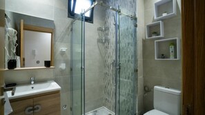 Un bagno moderno con doccia vetrata, lavandino con specchio e servizi igienici.