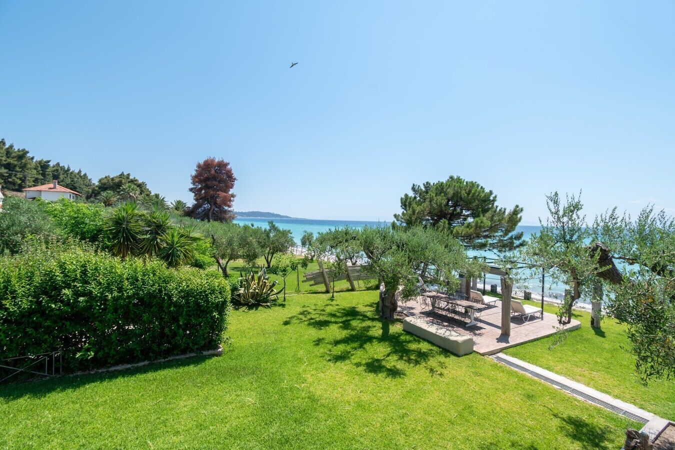 Un espace extérieur verdoyant, aménagé avec un coin salon et offrant une vue sur la mer.