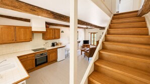 Una cocina con armarios de madera, lavavajillas y un comedor con mesa y sillas.