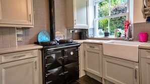Una cocina con estufa, gabinetes, una ventana y un lavabo.