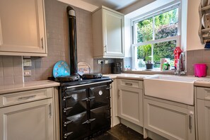 A kitchen with a stove, cabinets, a window, and a sink.