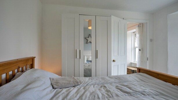 Un dormitorio con cama, armario y puerta que da a otra habitación.