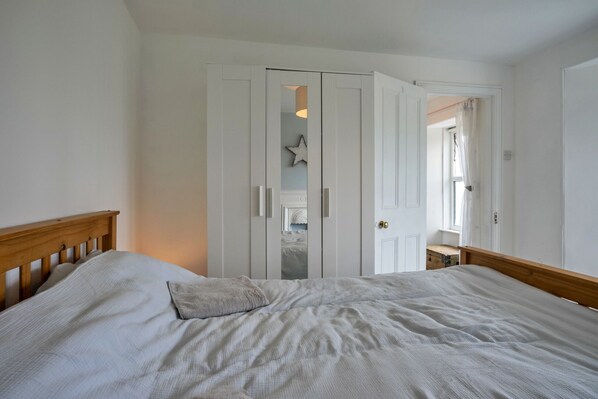 A bedroom with a bed, a wardrobe, and a door leading to another room.