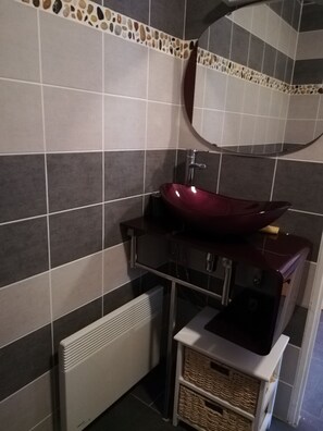 Ein Badezimmer mit einem roten Waschbecken, einem Spiegel und einer gefliesten Wand.