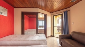 A room with two beds, a brown leather sofa, a red wall, and a balcony with a view. - Hotel Waikiki Beach Praia Azul (Natal)