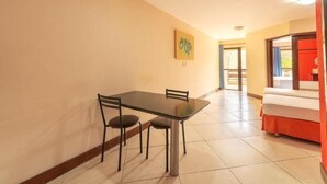 A hotel room with a bed, a dining table with chairs, a painting on the wall, and a door leading to another room. - Hotel Waikiki Beach Praia Azul (Natal)