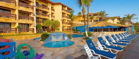 Un hotel con piscina, sillas de descanso y una palmera.