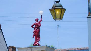 A statue of a woman on a pedestal with a street lamp above.