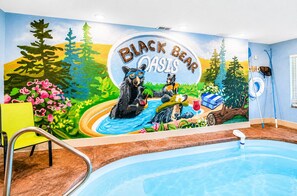 A pool area with a mural of bears and the text 'Black Bear Oasis.' - 2 bed cabin w/ Indoor Pool & Gameroom (Sevierville)