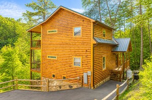 A log cabin with a porch, stone steps, and a fenced area. - 2 bed cabin w/ Indoor Pool & Gameroom (Sevierville)